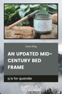 An open jar of Smoky Mountains Silk All-In-One Mineral Paint sitting on a brown rock with greenery in the background. A paint brush with paint on the bristles sits across the top of the jar. The words "an updated mid-century bed frame" are printed below the paint jar. The entire background of the picture is a photo of the Great Smoky Mountains.