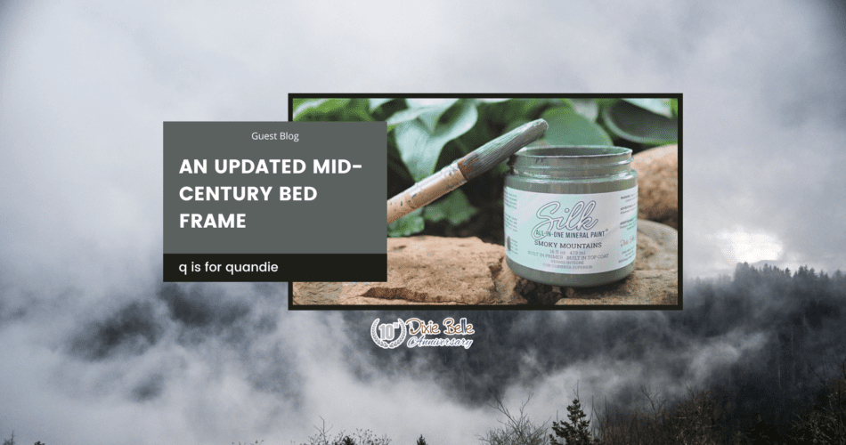 An open jar of Smoky Mountains Silk All-In-One Mineral Paint sitting on a brown rock with greenery in the background. A paint brush with paint on the bristles sits across the top of the jar. The words "an updated mid-century bed frame" are printed to the left of the paint jar. The entire background of the picture is a photo of the Great Smoky Mountains.