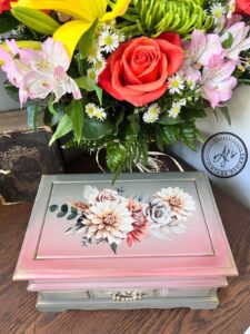 a painted jewelry box with Autumn Morning transfer applied to top sitting on a brown wooden table in front of a bouquet of flowers