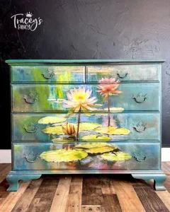 Dresser painted with a blend of various Chalk Mineral Paint colors that has the Lily Pads decoupage paper applied to the front of it sitting on a brown wooden floor, in front of a black painted wall