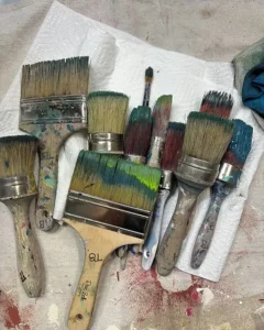 A variety of used paint brushes sitting on a table