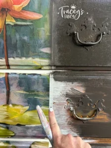 Close up of painted drawers that have Lily Pads decoupage paper with a finger pointing to the seam of the paper.