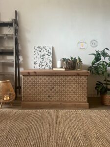 A wooden blanket box stained with No Pain Gel Stain sitting on a brown rug in front of a white wall