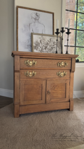 A nightstand stained with Whiskey Barrel Voodoo Gel Stain sitting on brown carpeted floor with candlesticks and photos on top of it.