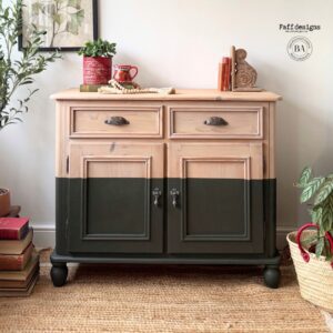 A buffet stained with Fireside Ash Voodoo Gel Stain on the top half and painted with Collard Greens Chalk Mineral Paint on the bottom half sitting on a brown rug in front of a white wall. A pile of books is on the floor to the left and a plant in a basket is on the floor to the right of the buffet.