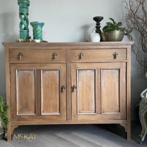 A buffet stained with Charred Hickory Voodoo Gel Stain sits on a wooden floor with candlesticks and plants sitting on top.